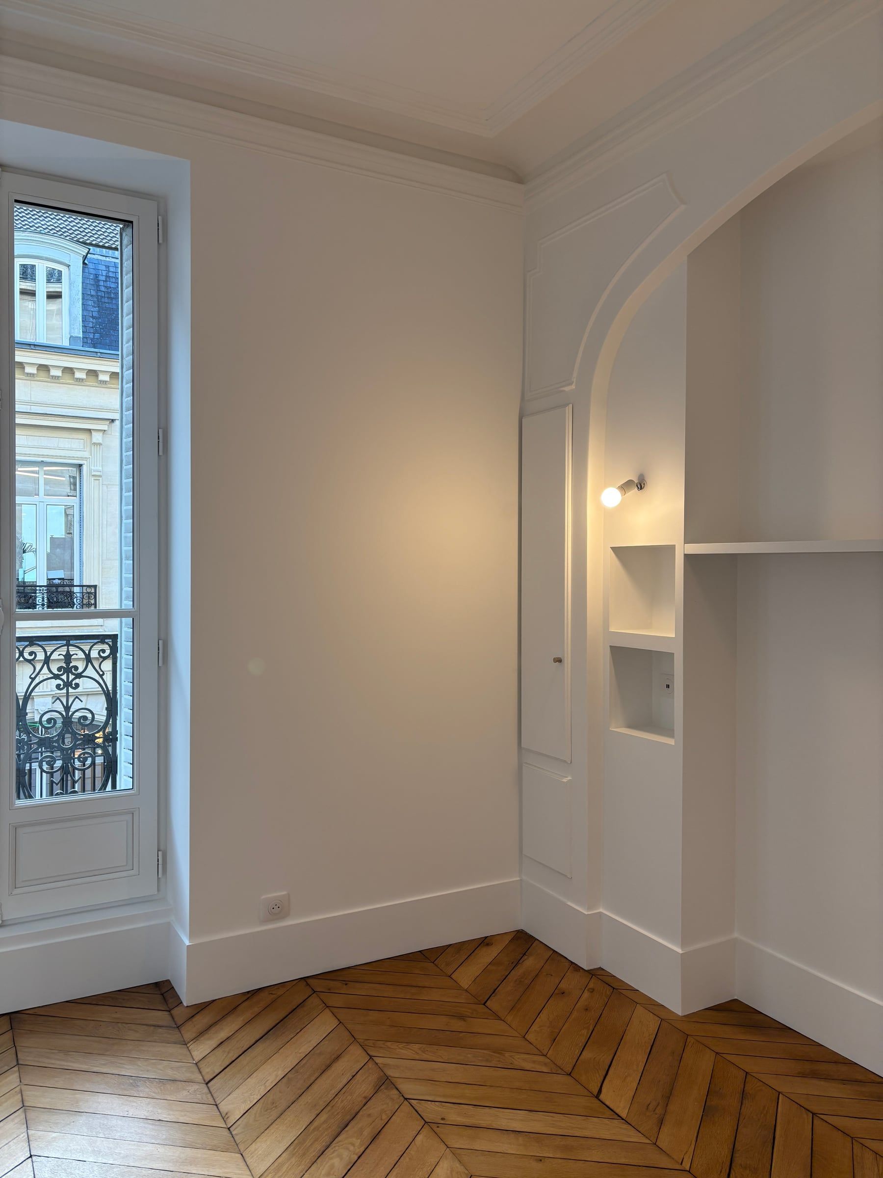 Angle de pièce au parquet point de Hongrie, niche voûtée à étagères et corniches moulurées issu d'une rénovation de maison.