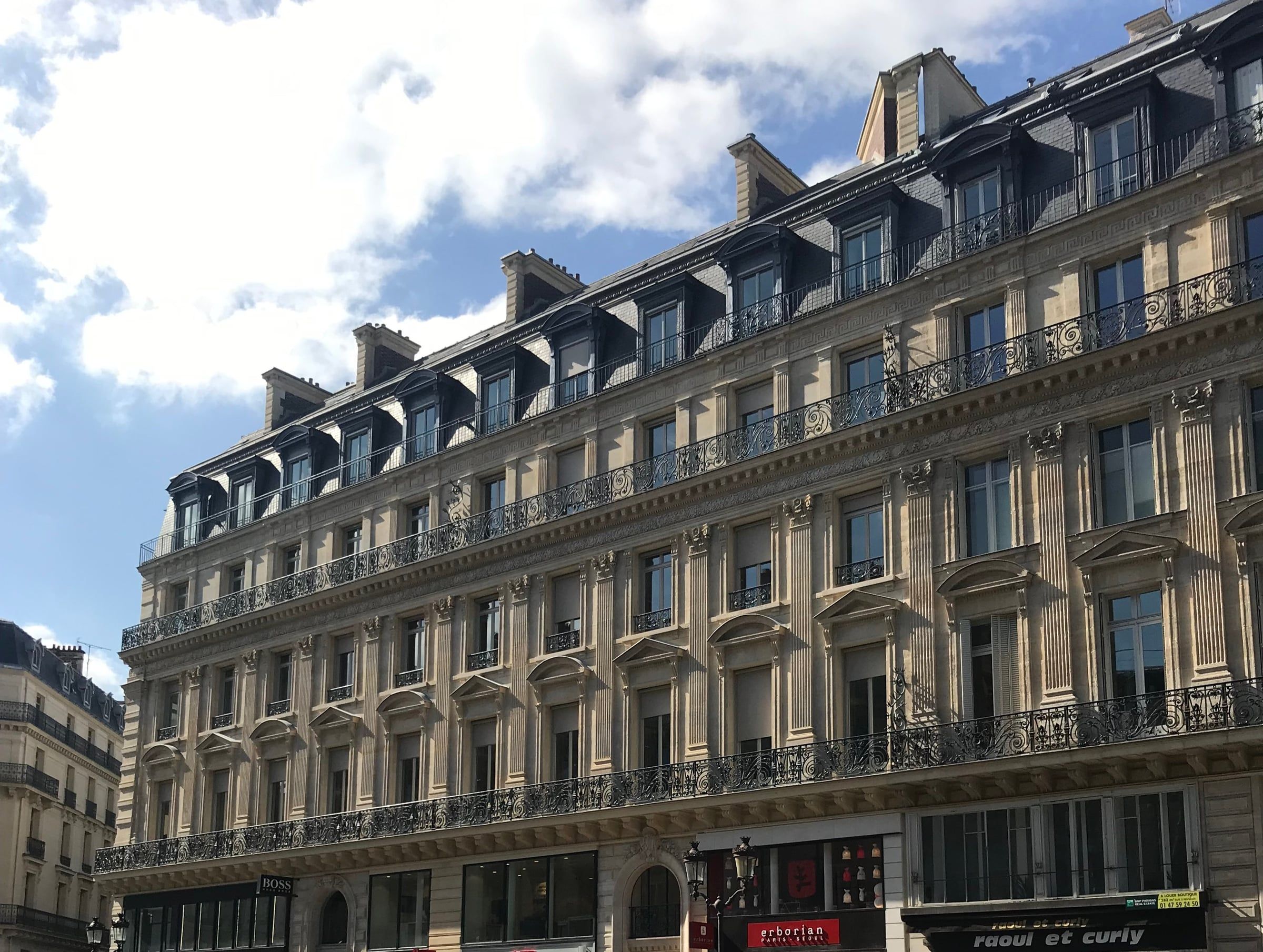 Façade haussmannienne en pierre de taille avenue de l'Opéra, balcons en fer forgé et toiture en zinc, ravalement de façade par un architecte d'intérieur à Paris