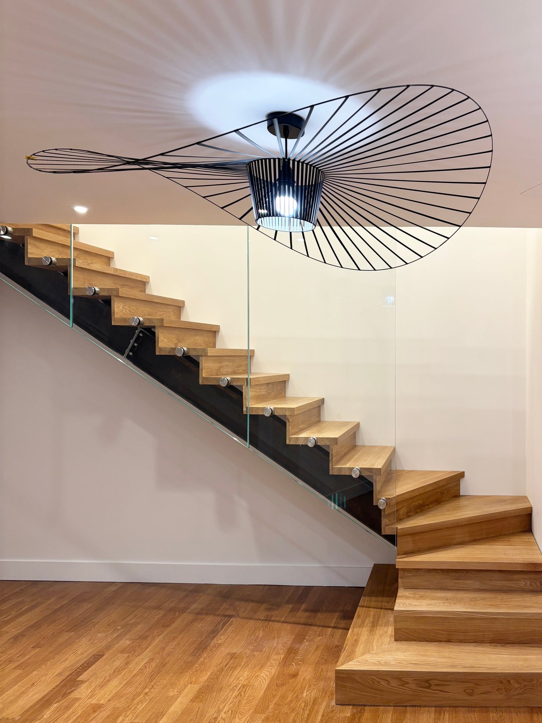 Escalier de bureaux à crémaillère noire et marches en chêne, garde-corps en verre et suspension Vertigo noire, aménagement de bureaux sur mesure
