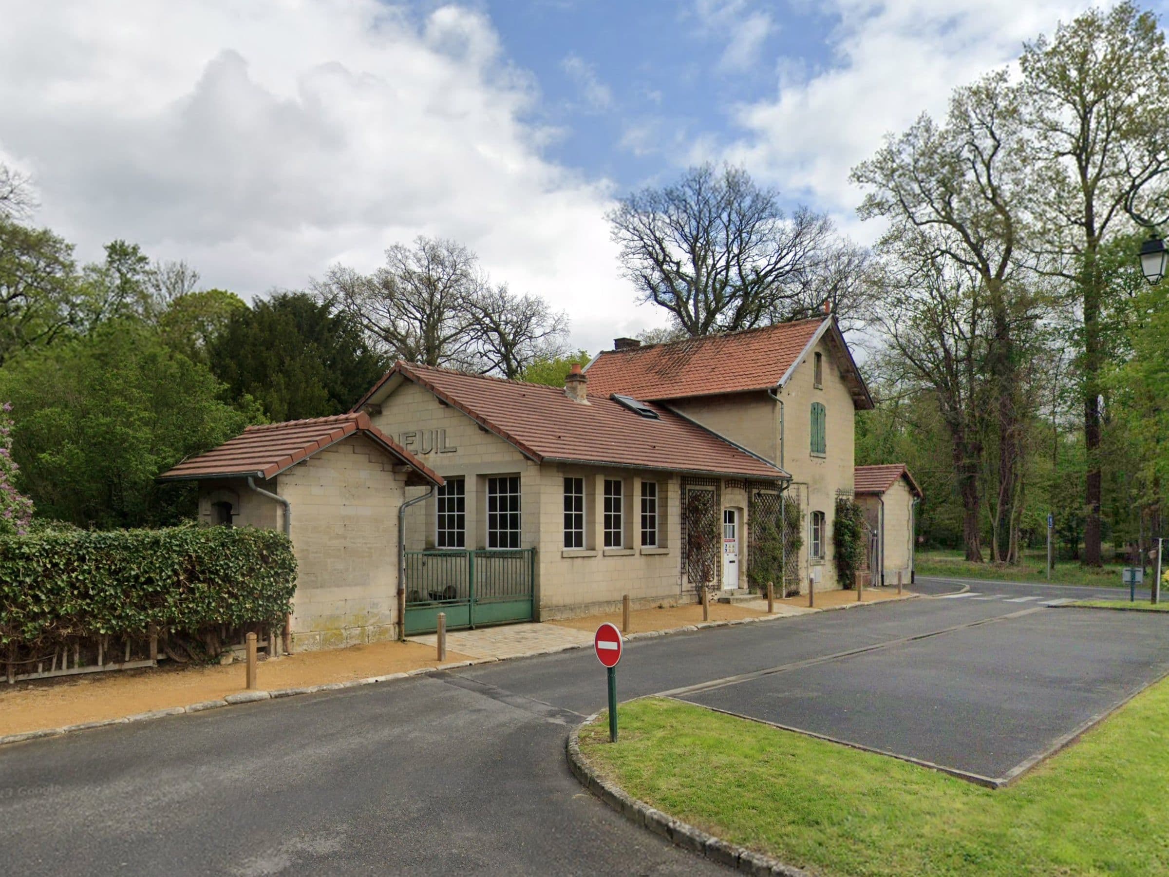 Avant travaux : ancien bâtiment en pierre de type gare à toiture en tuiles, portail vert et fenêtres d'origine, en bordure de route boisée.