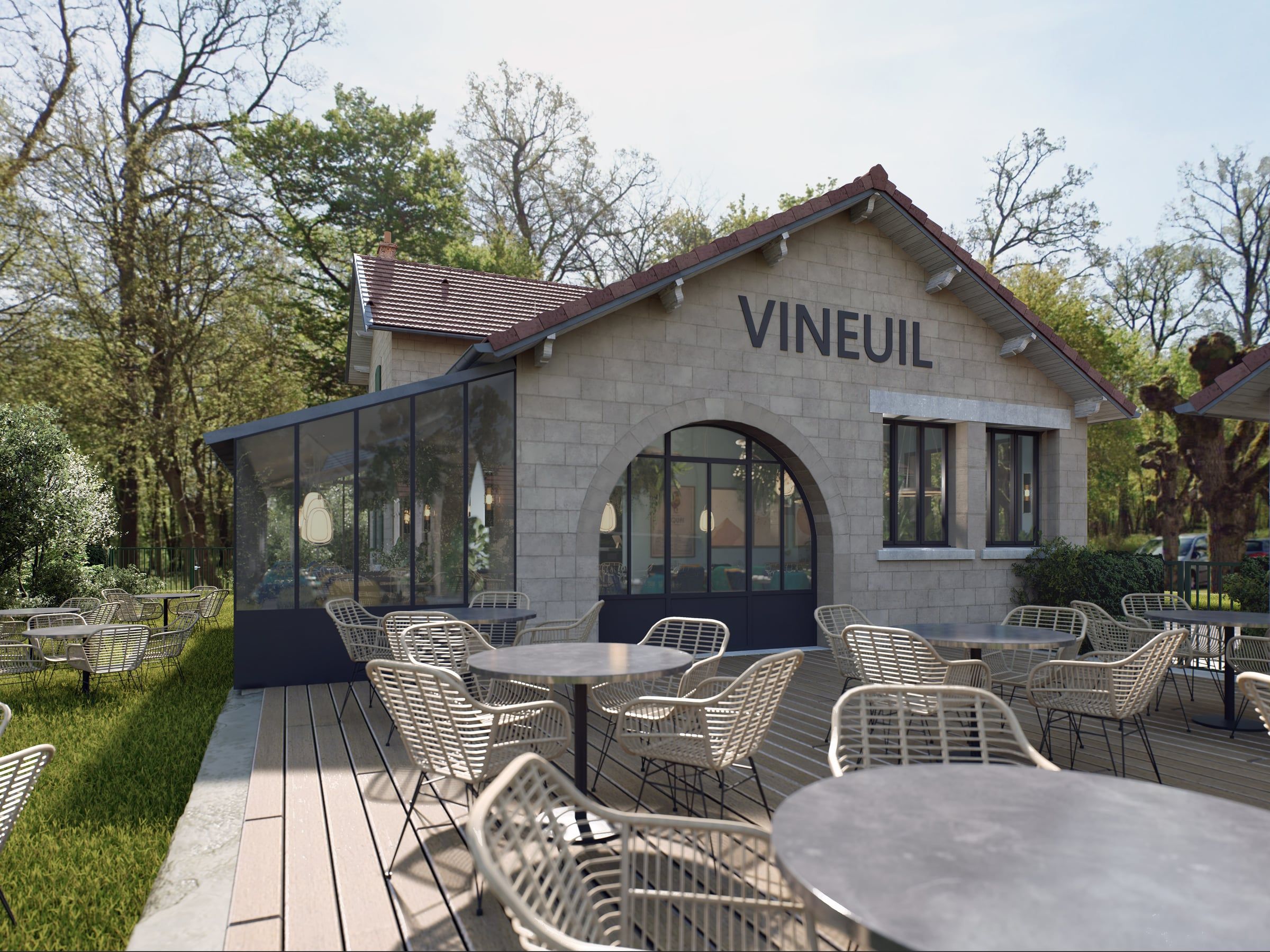 Façade en pierre de taille du restaurant Le Quai avec véranda vitrée et terrasse en bois garnie de fauteuils tressés, sous les arbres.