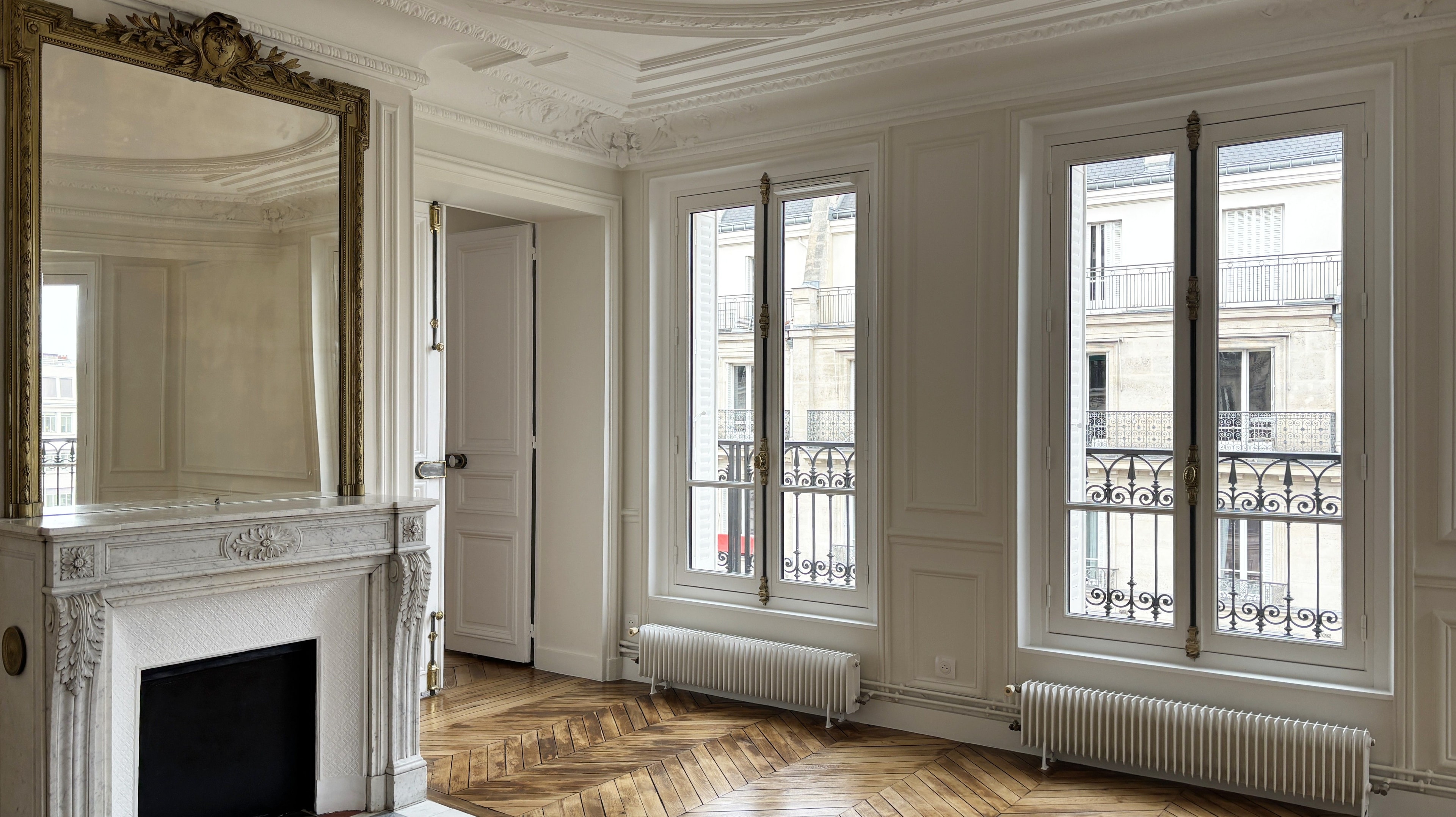 Bureau contemporain aux rangements toute hauteur, bibliothèque ajourée modulaire et parquet en chevrons, aménagé par un architecte d'intérieur.