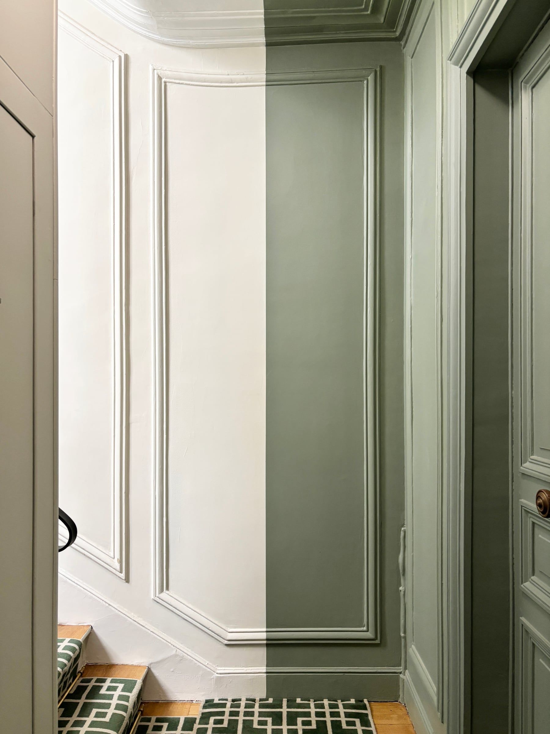 Détail d'une mise en peinture en cours, panneau mouluré séparé entre blanc d'origine et nouveau vert sauge, tapis géométrique en pied de mur, parties communes.