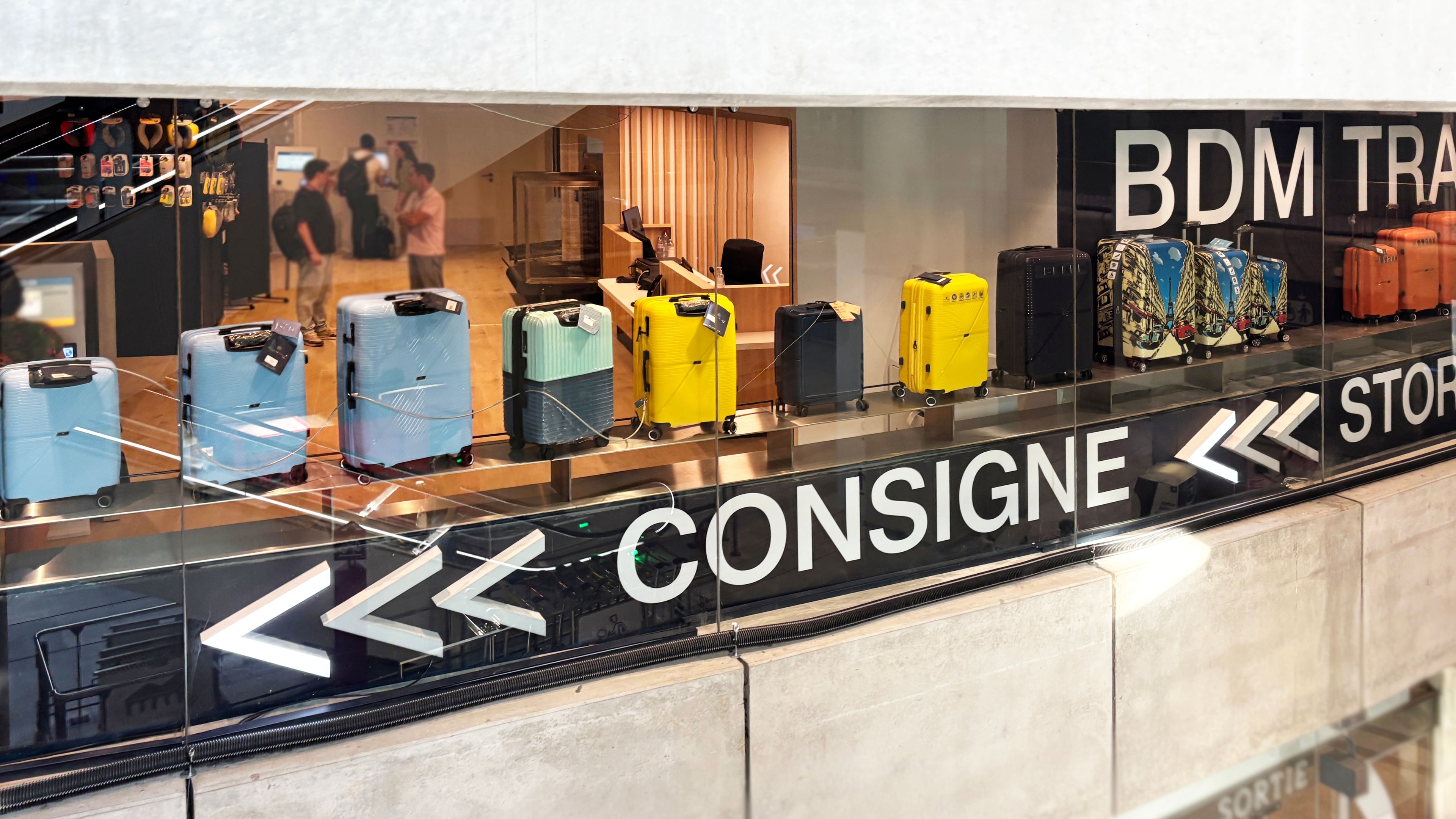 Commerce de consigne bagages rénové par un architecte d'intérieur, vitrine vitrée, signalétique noire et valises alignées en présentation.