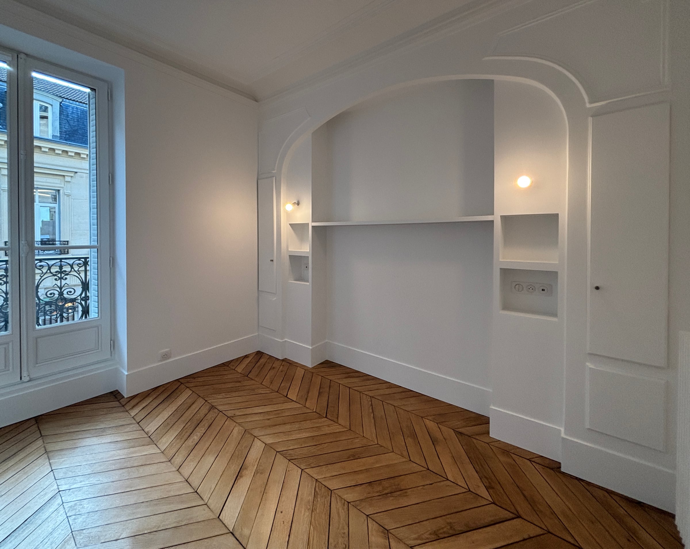 Pièce haussmannienne au parquet point de Hongrie et niche voûtée en plâtre rénovée par un architecte d'intérieur en résidentiel.