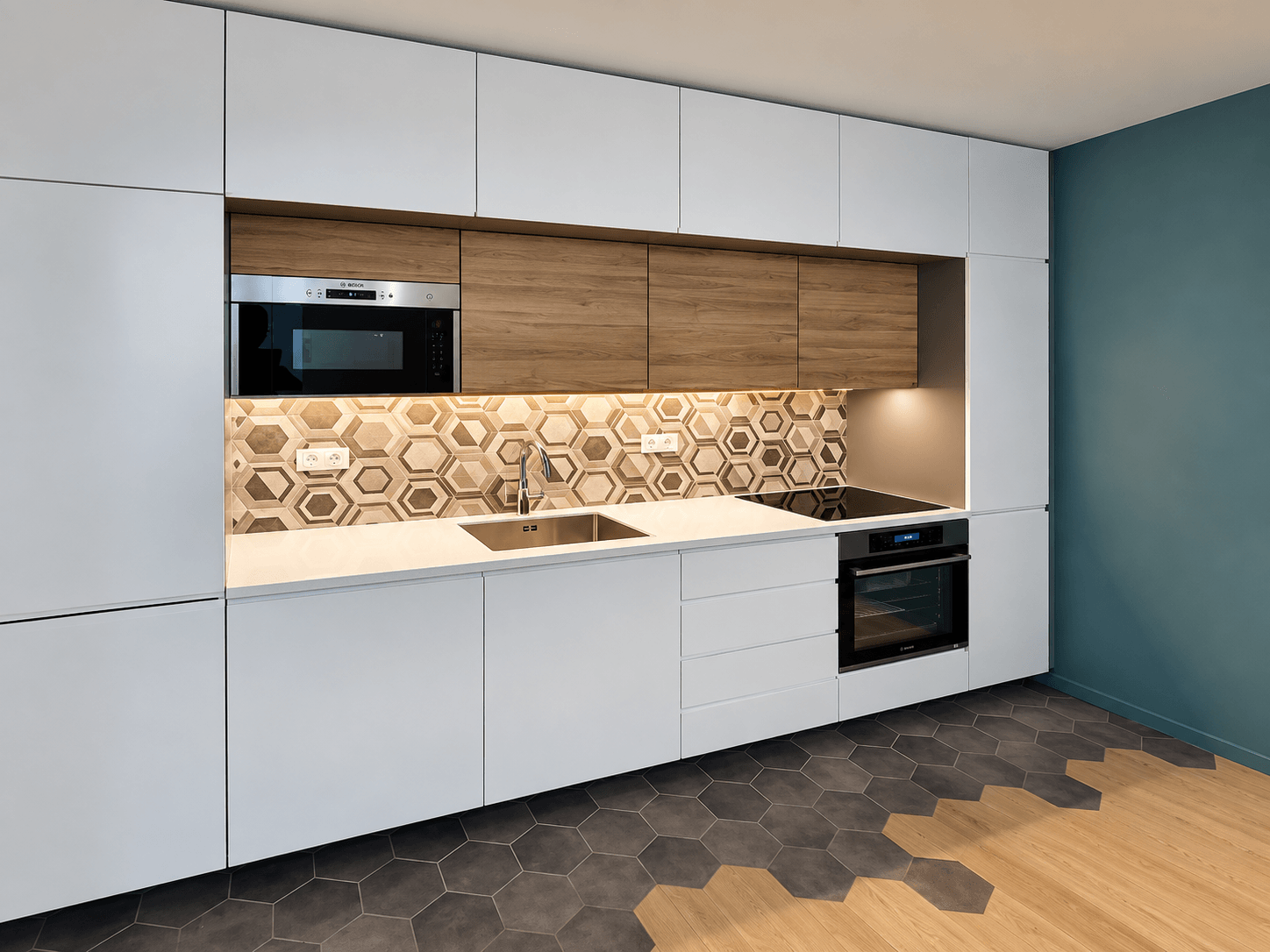Cuisine linéaire aux façades blanches et bois, crédence en carreaux hexagonaux et sol tomettes grises et chêne, rénovée par un architecte d'intérieur.